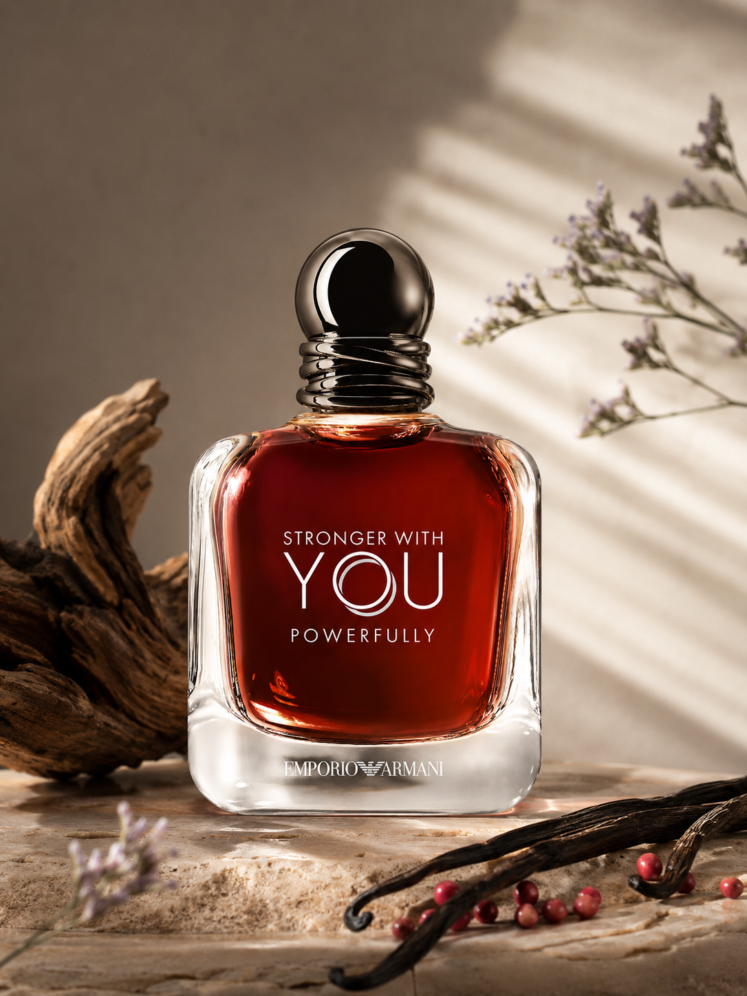 Emporio Armani Stronger With You Powerfully fragrance displayed in a warm elegant setting with driftwood, vanilla pods, pink pepper berries, and soft natural lighting.