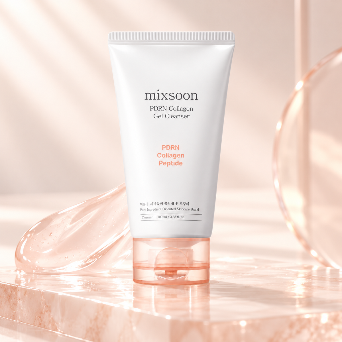 Mixsoon PDRN Collagen Gel Cleanser 100ml displayed on a glossy pink marble surface with a translucent gel texture, delicate peach tones and soft lighting. A Korean skincare cleanser featuring PDRN, collagen and peptides for gentle daily facial cleansing and smooth, refreshed-looking skin.